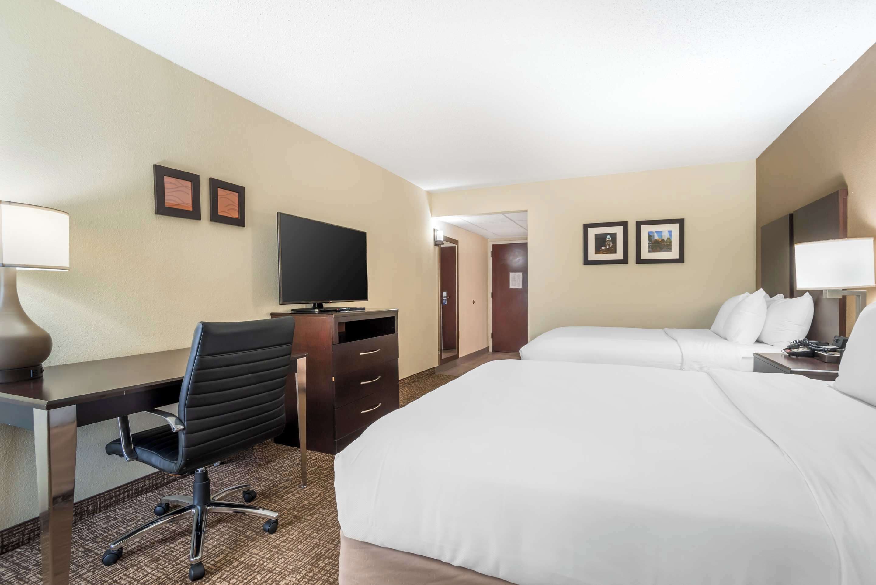 Une chambre d’hôtel comprenant un lit, un bureau avec une chaise, une télévision et une commode.