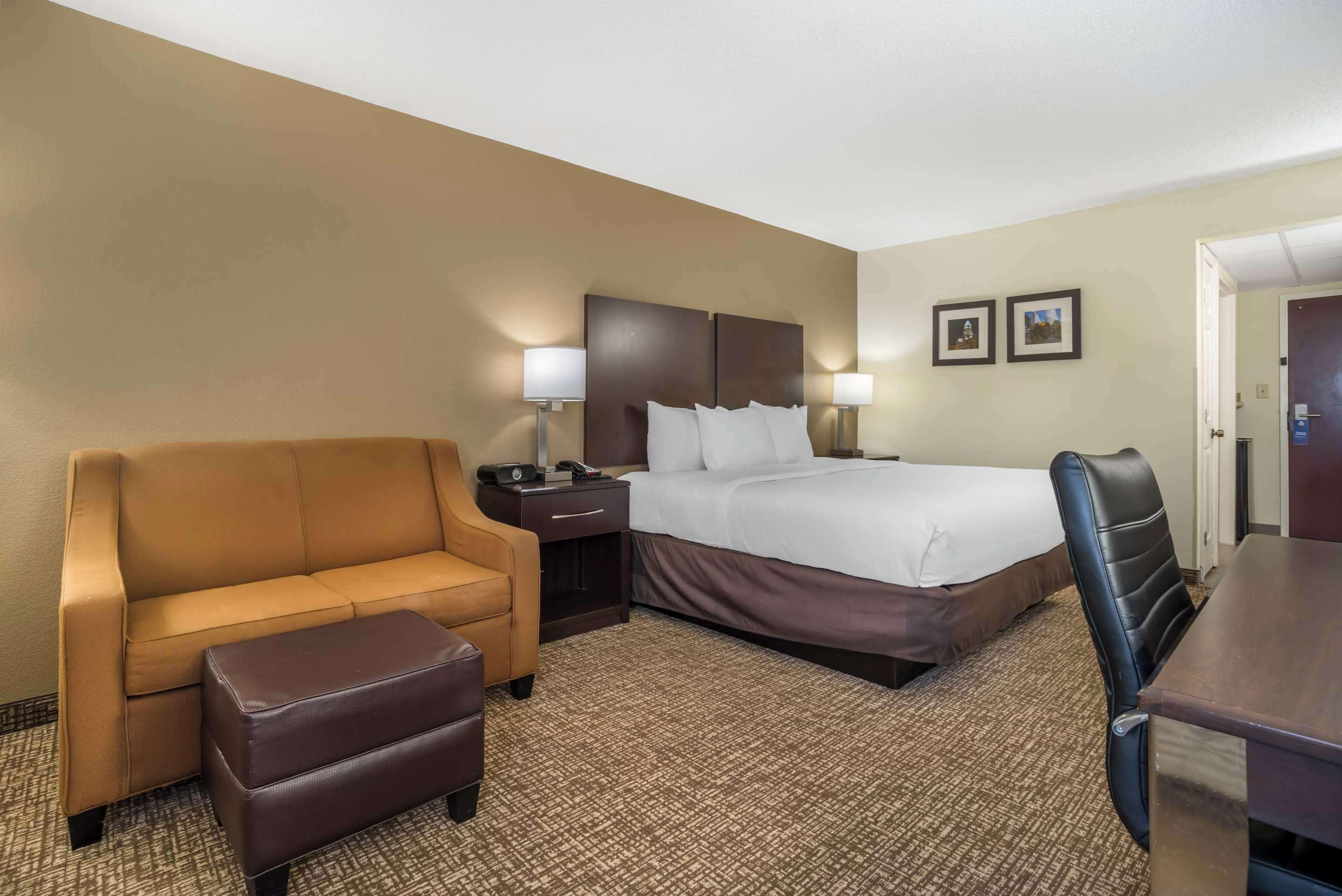 Une chambre d’hôtel comprenant un lit, un canapé, un pouf, un bureau et une chaise.