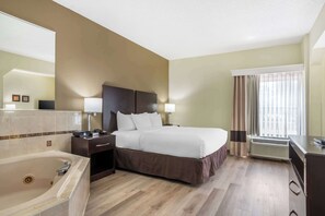 A hotel room with a large bed, a separate bathroom with a bathtub, a desk with a chair, and a window with curtains. - Comfort Inn & Suites Lake Norman (Cornelius)