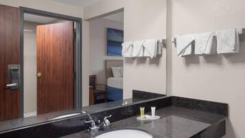 A bathroom with a large mirror, a sink, and towels on a rack.