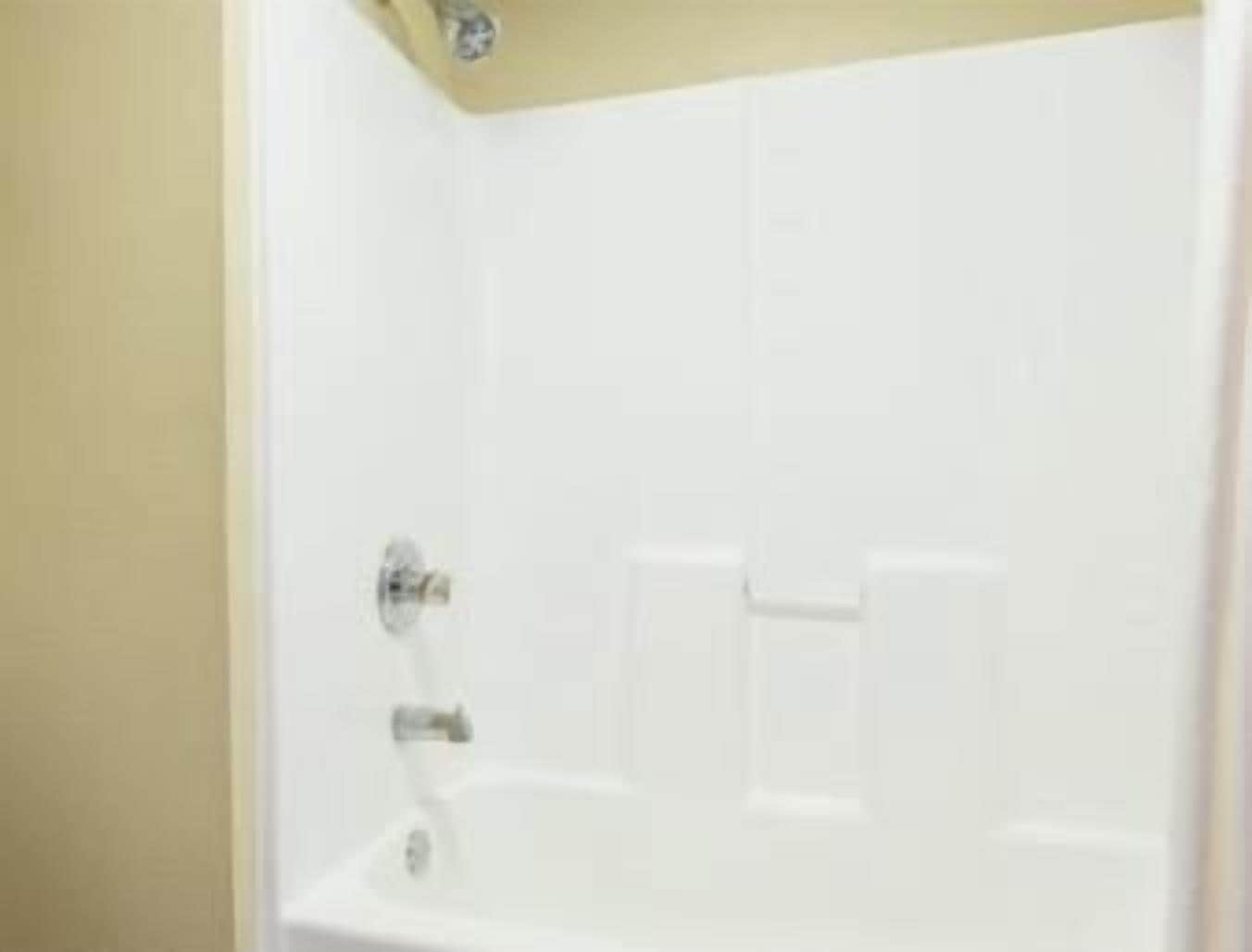 A white bathtub with a showerhead and a control panel.