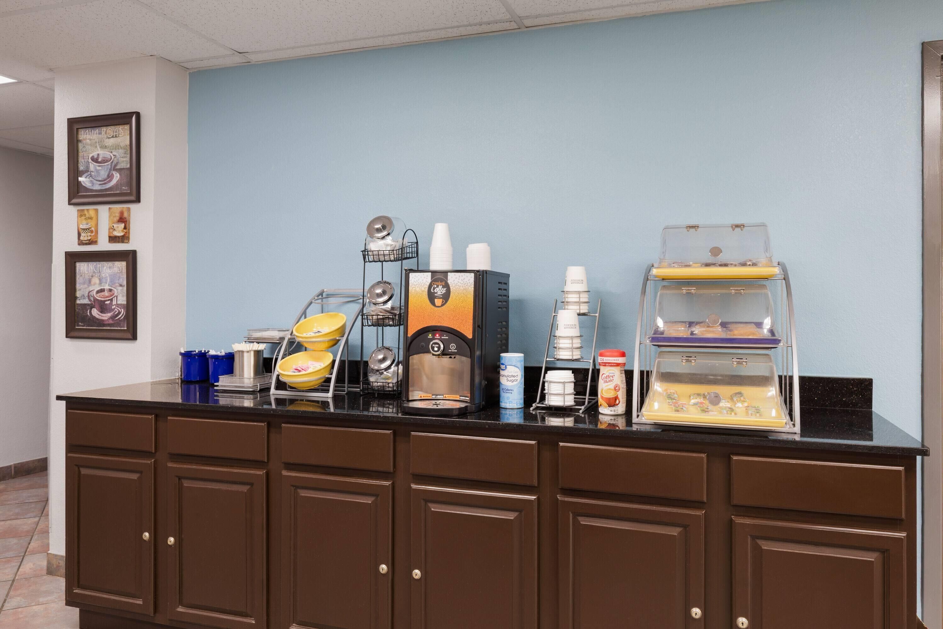 A coffee station with a coffee machine, cups, and a display case.