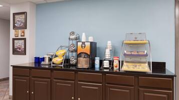 A coffee station with a coffee machine, cups, and a display case.