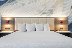 Ein Hotelzimmer mit einem großen Bett, einem hölzernen Kopfteil und zwei Nachttischen mit roten Lampen.