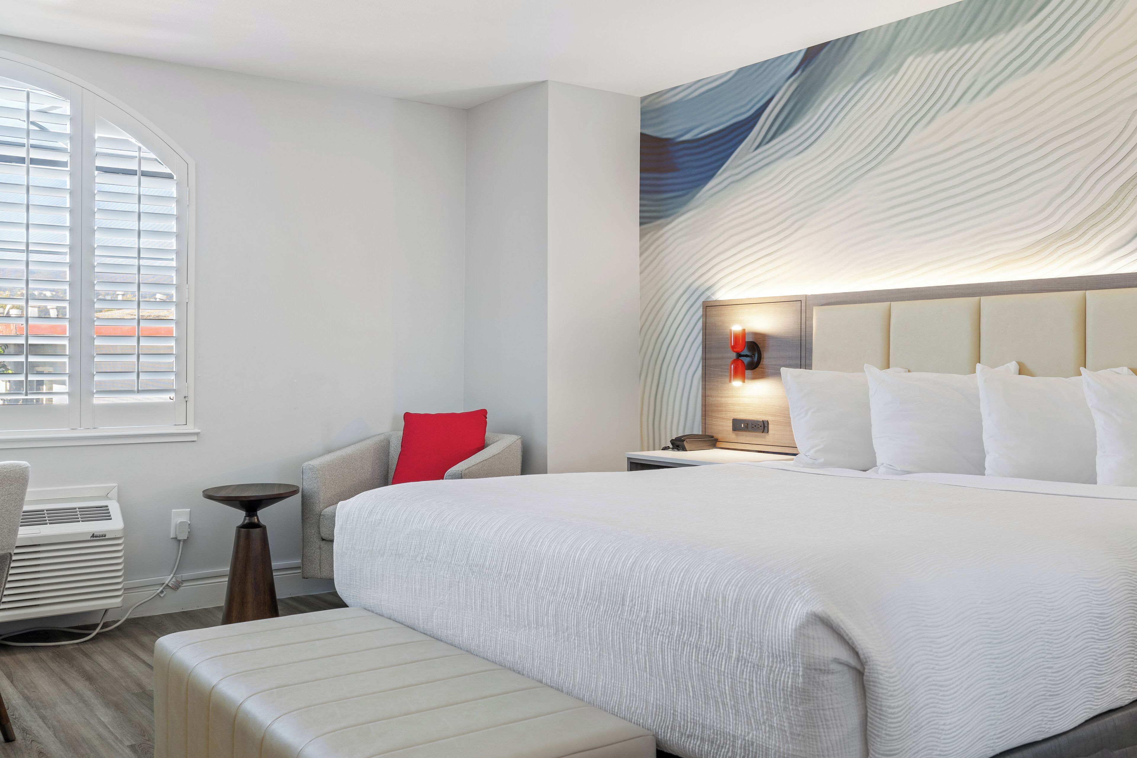 Una habitación de hotel moderna con una cama grande, una zona de estar pequeña y vistas por la ventana.