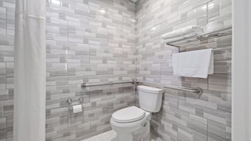 Un baño moderno con inodoro, barras de apoyo y un perchero para toallas.