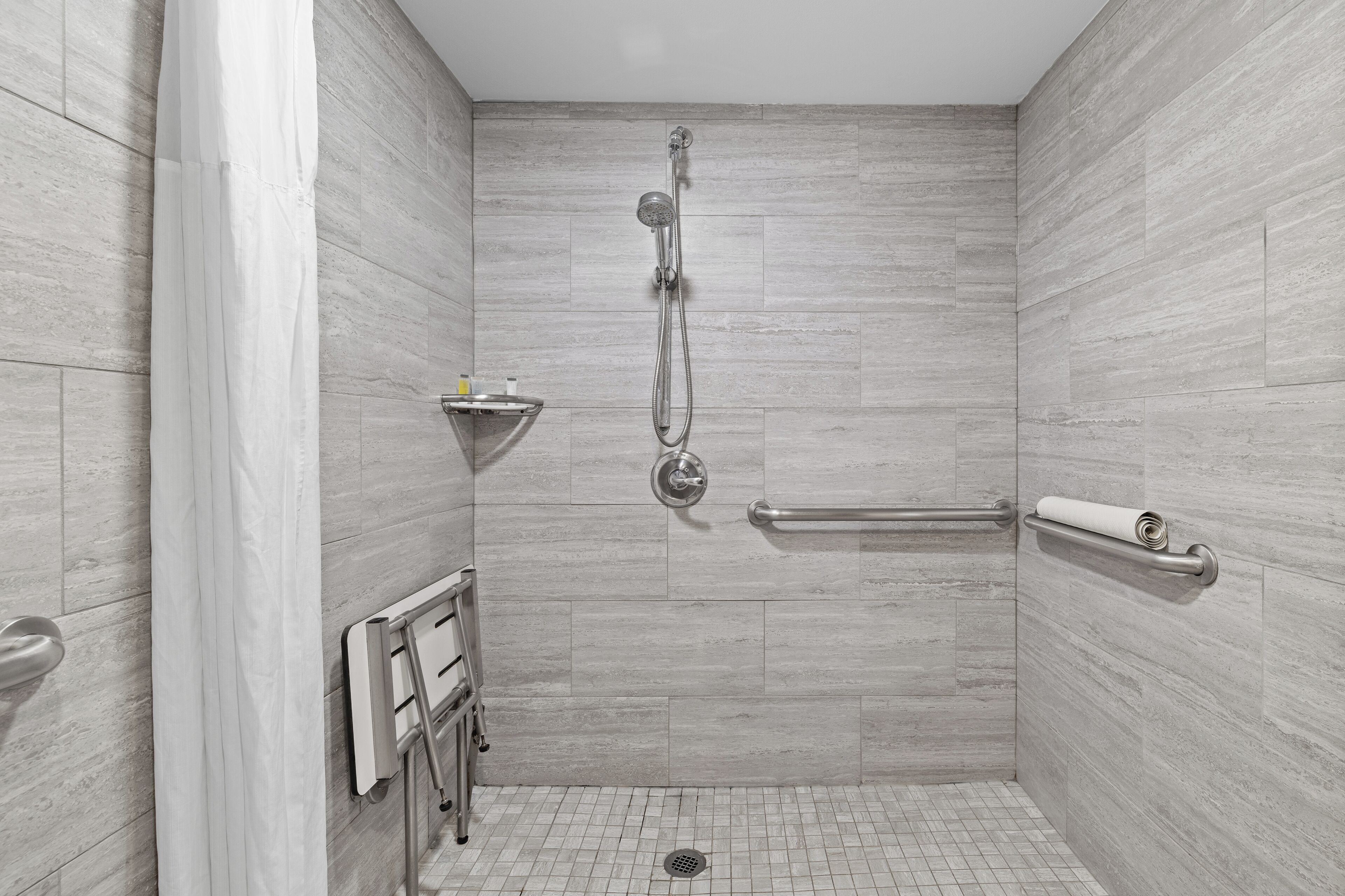 Un bagno moderno con doccetta a mano, portasciuga e barra di sostegno.