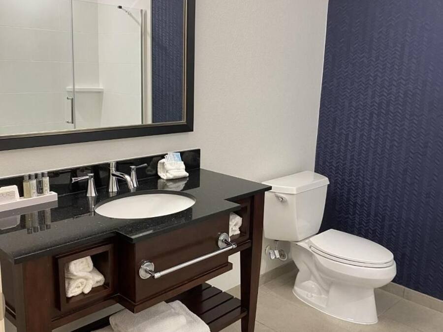 Une salle de bain avec un meuble-lavabo en bois foncé, un lavabo blanc et des toilettes.