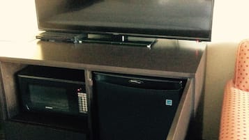 A compact kitchenette with a microwave, refrigerator, and a flat-screen TV.
