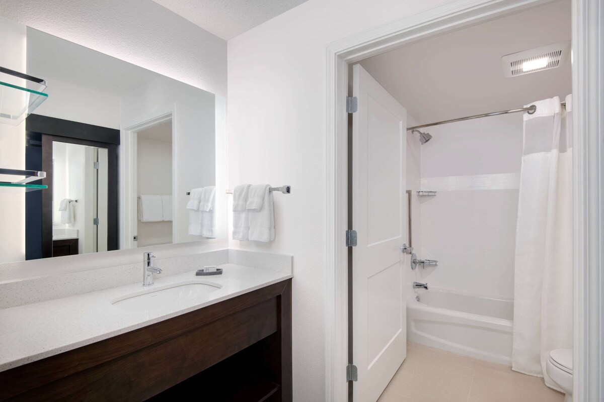 A modern bathroom with a white vanity, a large mirror, a shower with a glass door, and a toilet.
