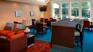 Een hotel lobby met een bar, zitplaatsen en kunstwerken aan de muren.