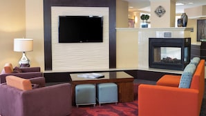 Un hall d’hôtel doté d’un téléviseur à écran plat, d’une cheminée et de sièges confortables.