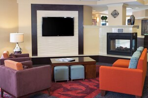 Un vestíbulo de hotel con un televisor de pantalla plana, chimenea y asientos cómodos.
