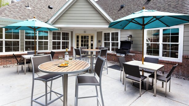 Un espace patio aménagé avec des sièges d’extérieur, un barbecue et des parasols.