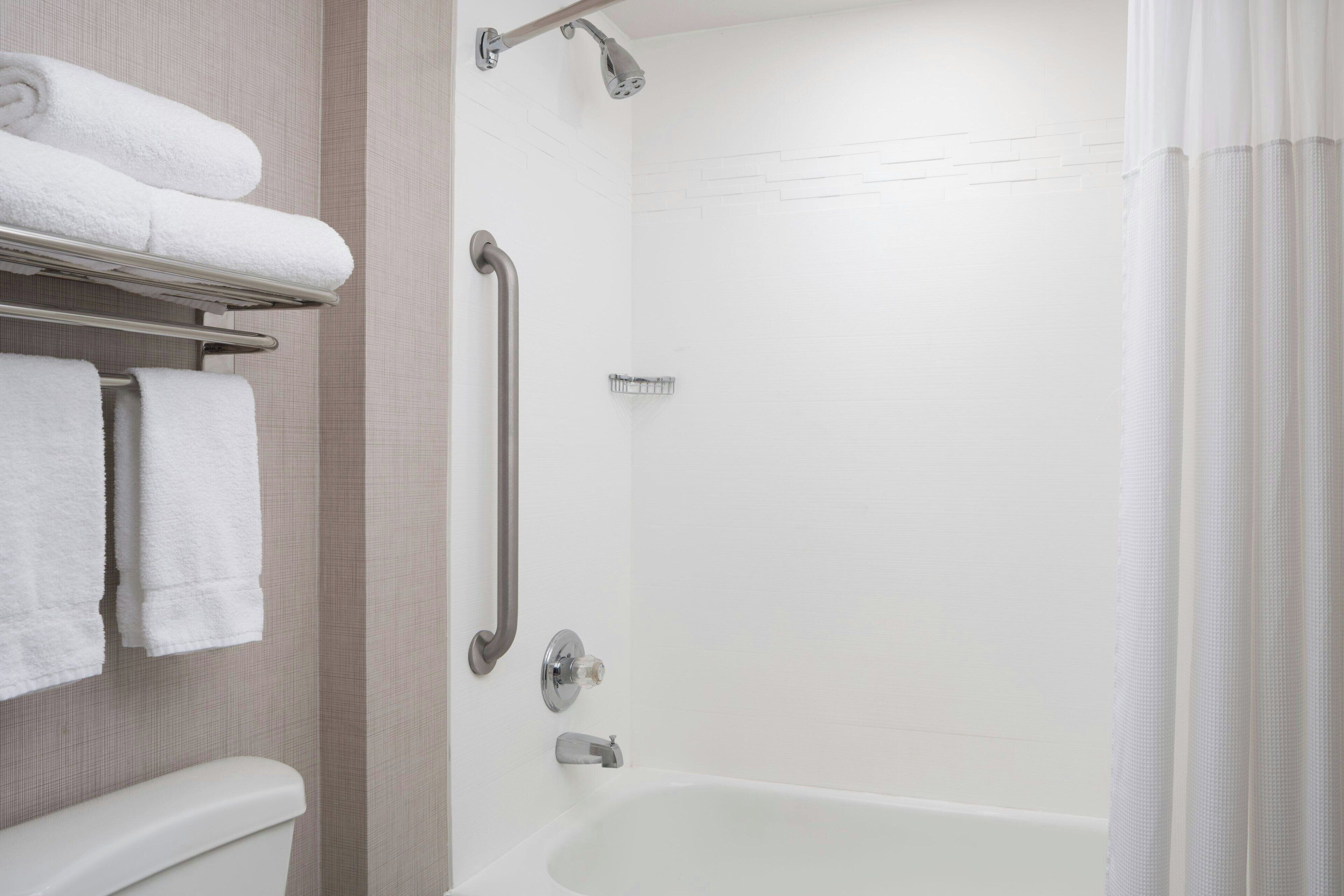 A modern bathroom with a walk-in shower, grab bars, and a bathtub.