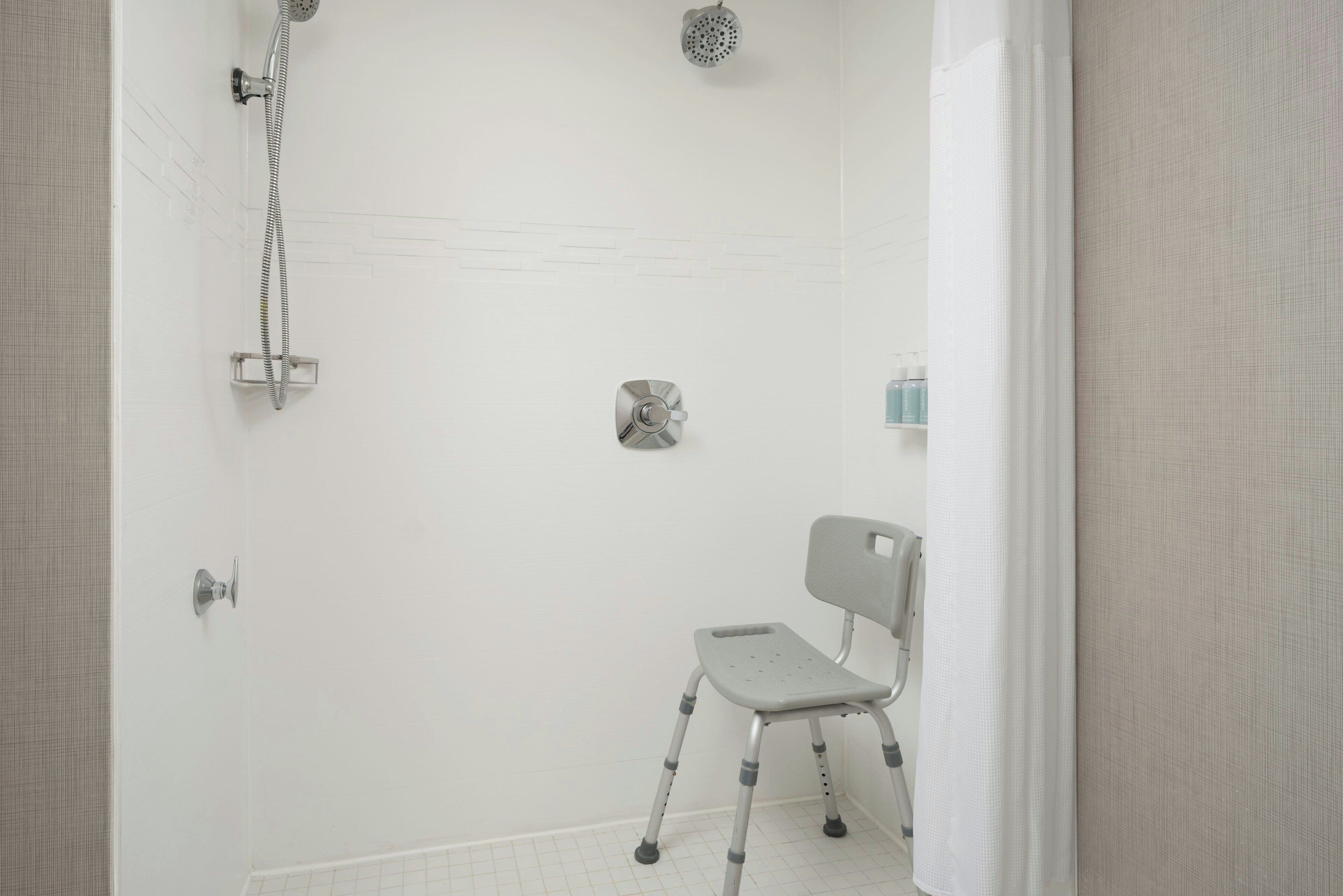 Un baño con ducha, una silla y un inodoro.