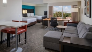 A hotel room with a bed, a desk, a sofa, and a dining area. - Residence Inn by Marriott Orlando Convention Center (Orlando)