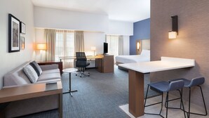 Una habitación de hotel moderna con sofá, escritorio y zona de bar.