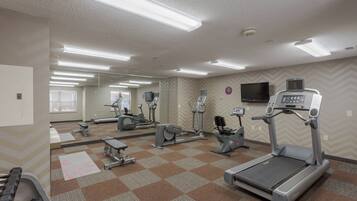 Une salle de sport équipée de divers appareils d’exercice, notamment des tapis de course, des vélos d’appartement et des appareils de musculation.