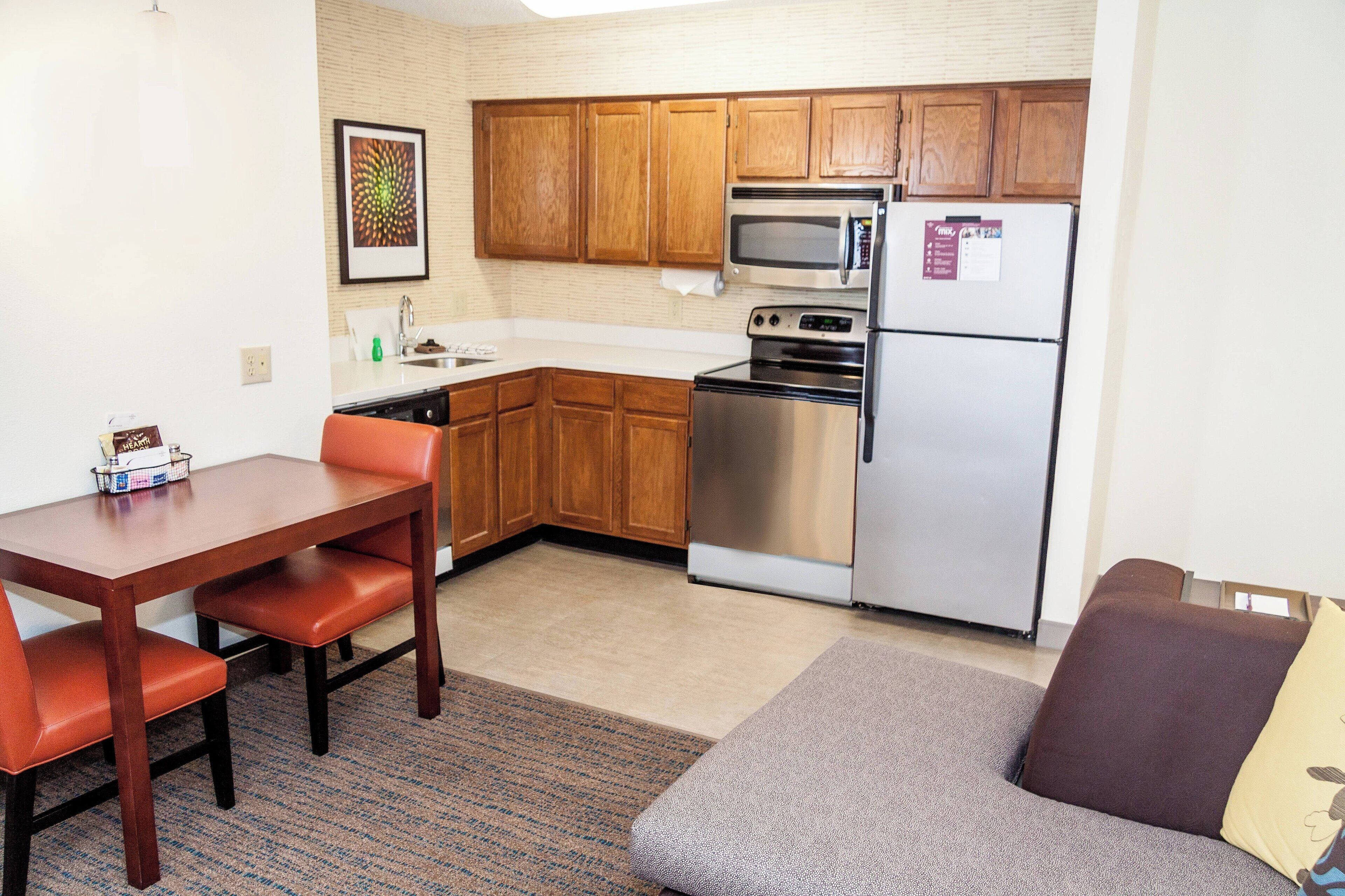 A compact kitchen with wooden cabinets, a microwave, an oven, and a refrigerator.