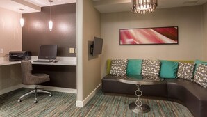 A modern hotel room with a desk, computer, and a comfortable seating area with a sofa and cushions. - Residence Inn by Marriott Rocky Mount (Rocky Mount)