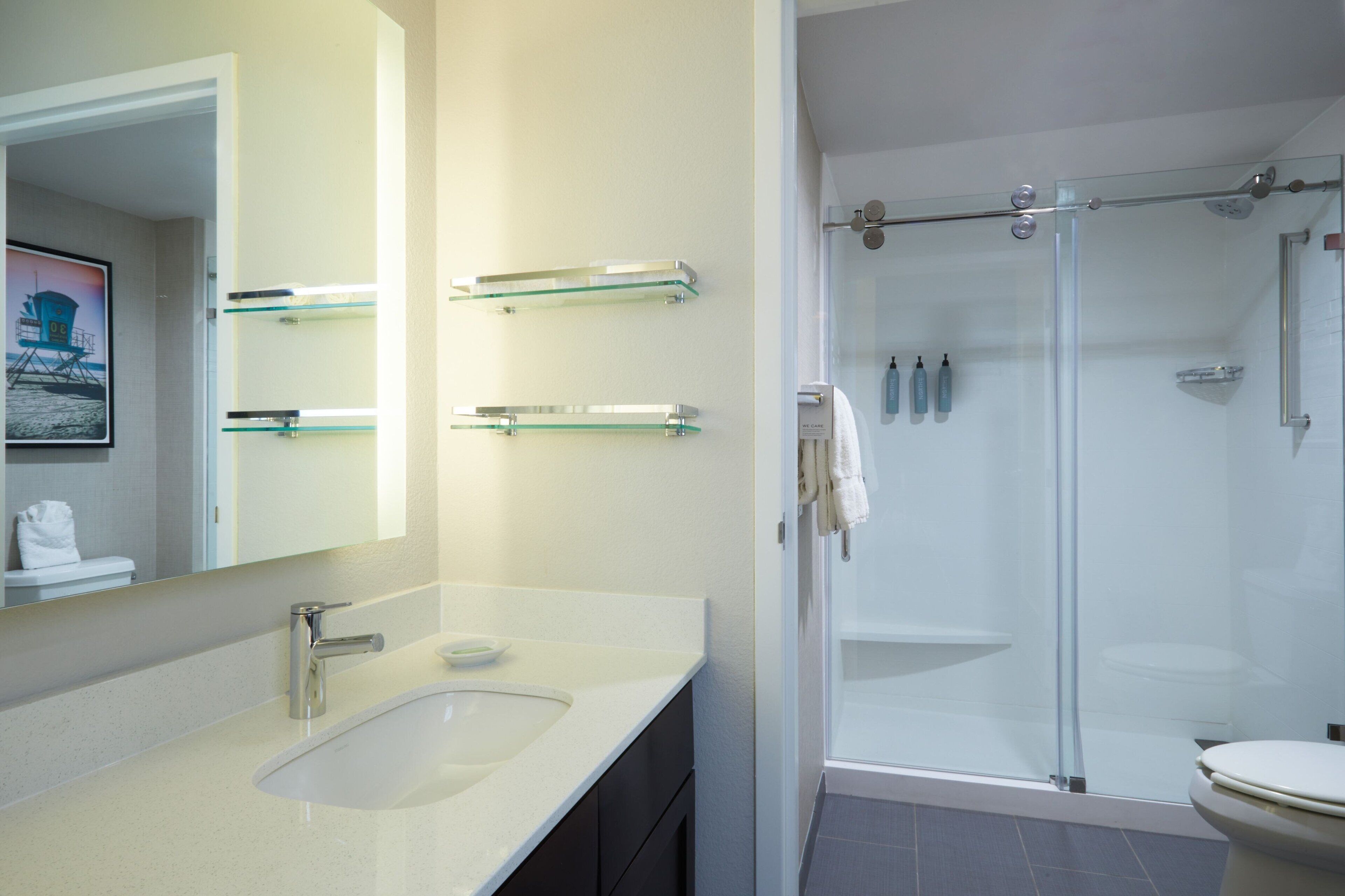 A modern bathroom with a glass shower enclosure, a sink with a soap dish, and a towel rack.