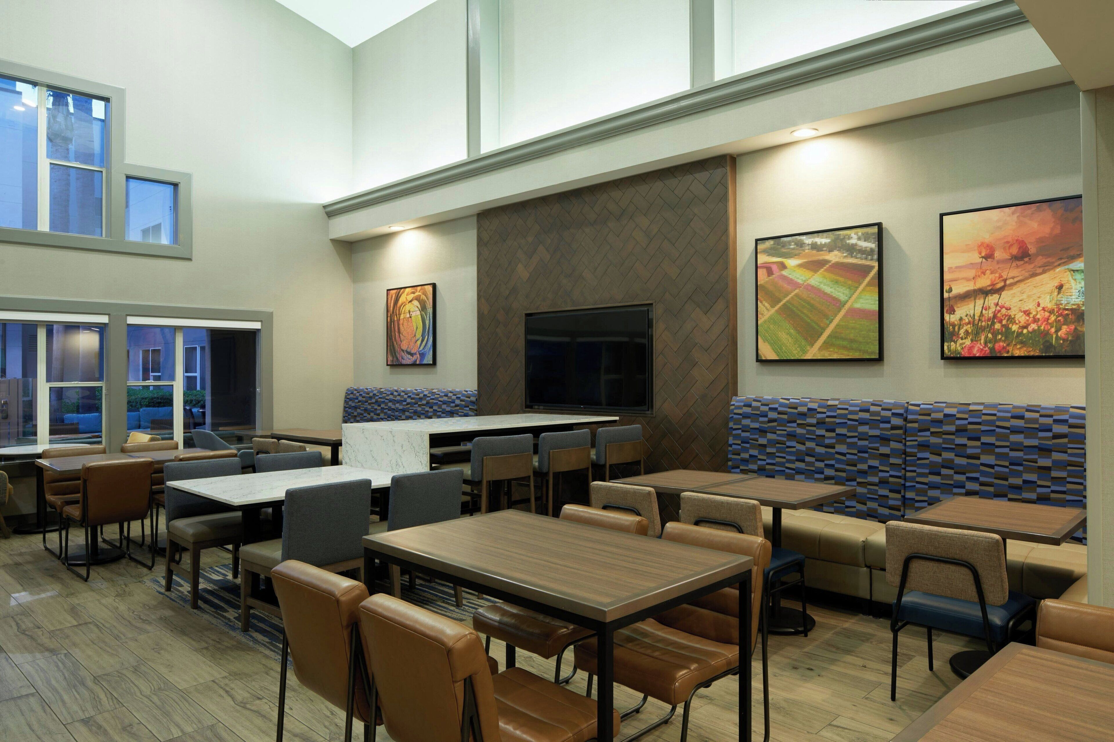 A spacious restaurant with high ceilings, large windows, and a variety of seating options including booths and tables.