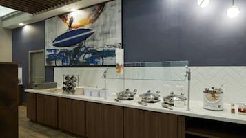 A modern kitchen with a white countertop, stainless steel appliances, and a large painting of a bicycle.