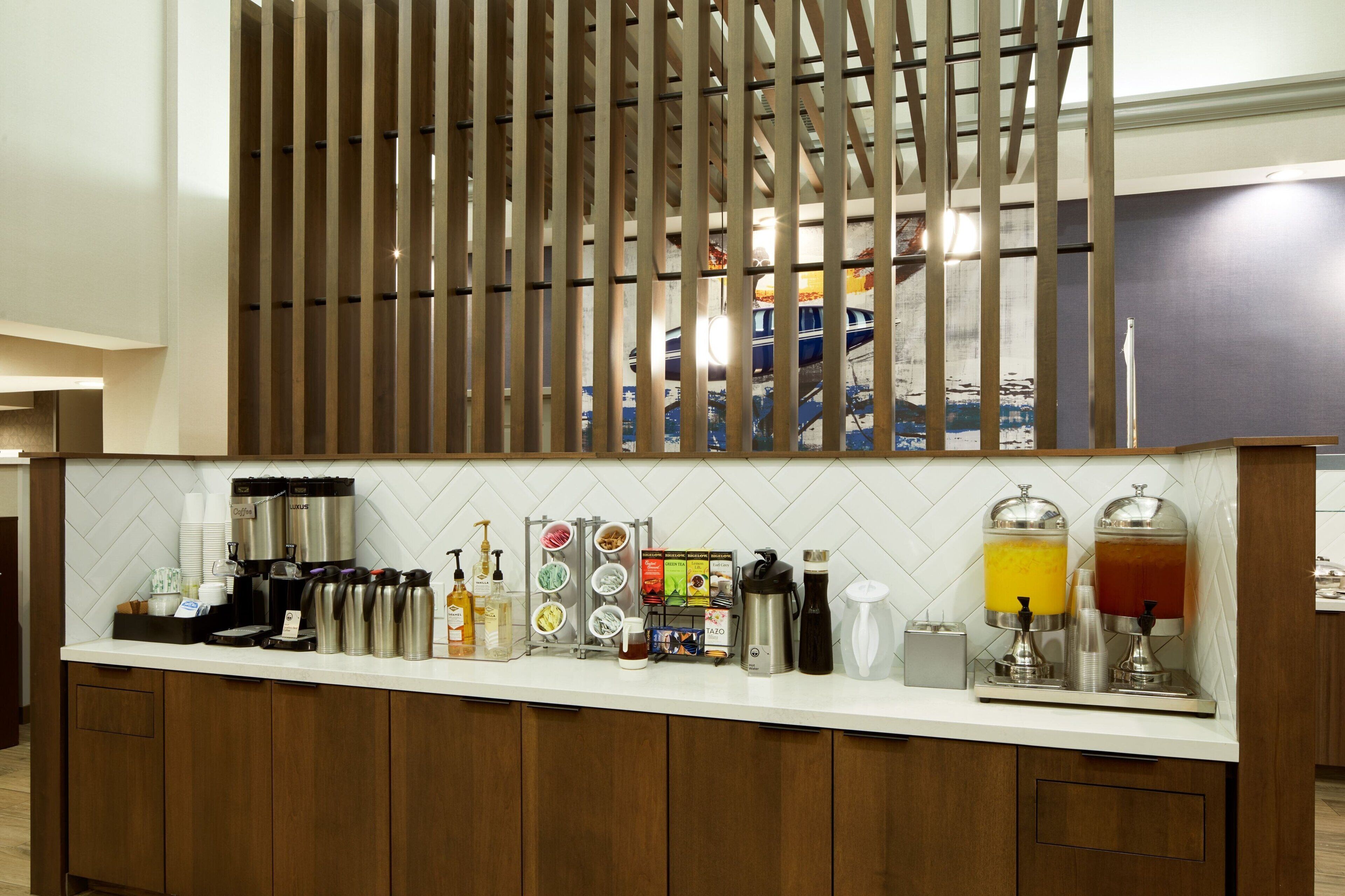 A bar area with a coffee station, including coffee makers, mugs, and a variety of beverages.