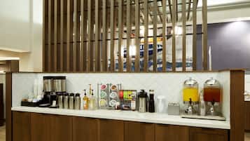 A bar area with a coffee station, including coffee makers, mugs, and a variety of beverages.