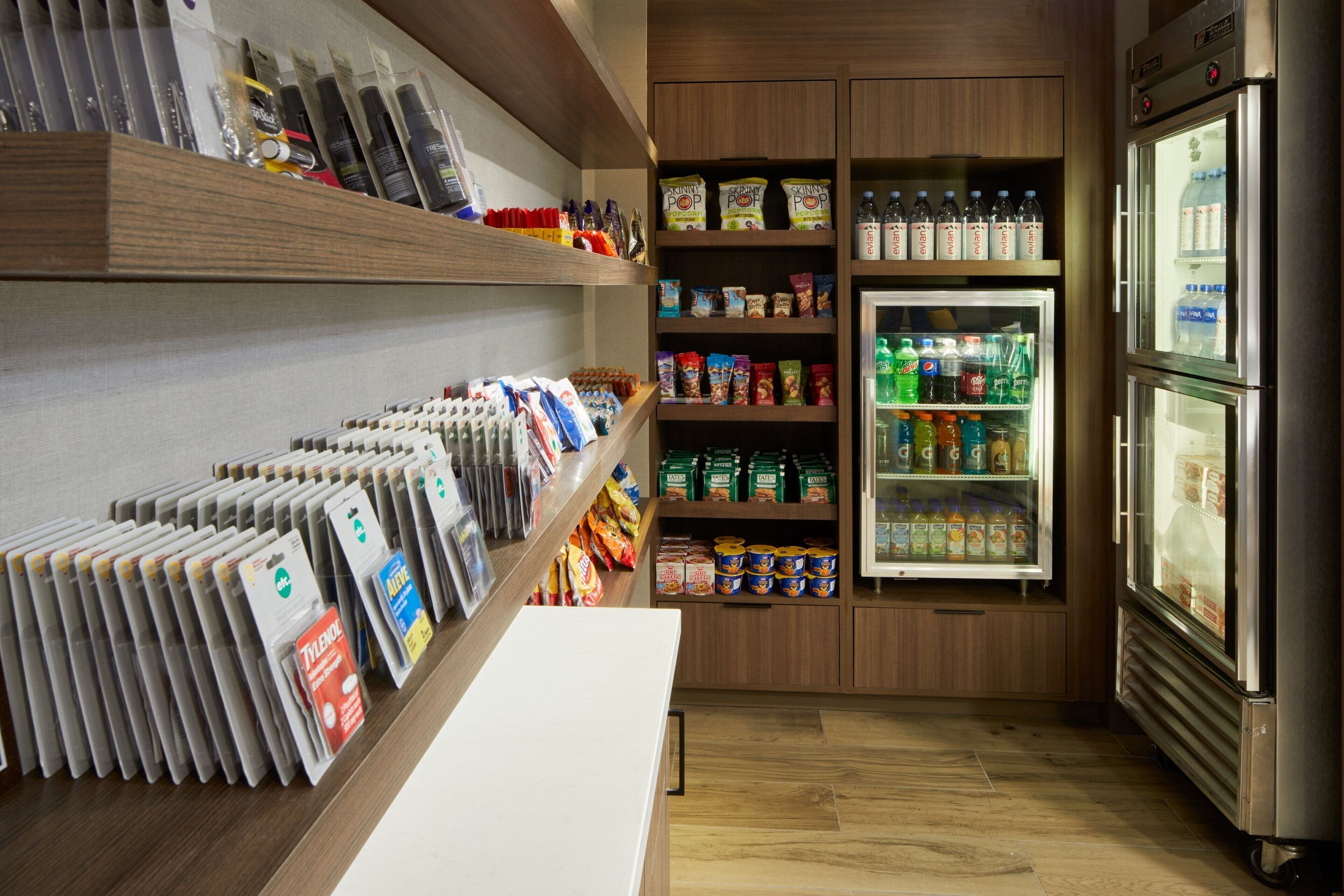 A well-organized store with shelves stocked with various products and a refrigerator with beverages.