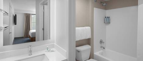 Un baño moderno con lavamanos, inodoro y bañera blancos.