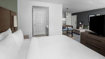 A hotel room with a large bed, a desk with two chairs, a television, and a wardrobe.