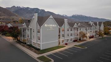 A multi-story hotel with a prominent sign reading "Residence INN BY MARRIOTT" in front of a mountainous backdrop.