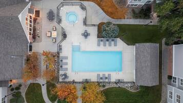 An aerial view of a residential area with a swimming pool, outdoor seating, and a landscaped garden.