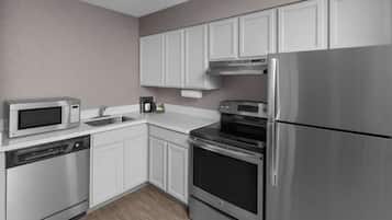 A modern kitchen with stainless steel appliances, white cabinetry, and a built-in oven.