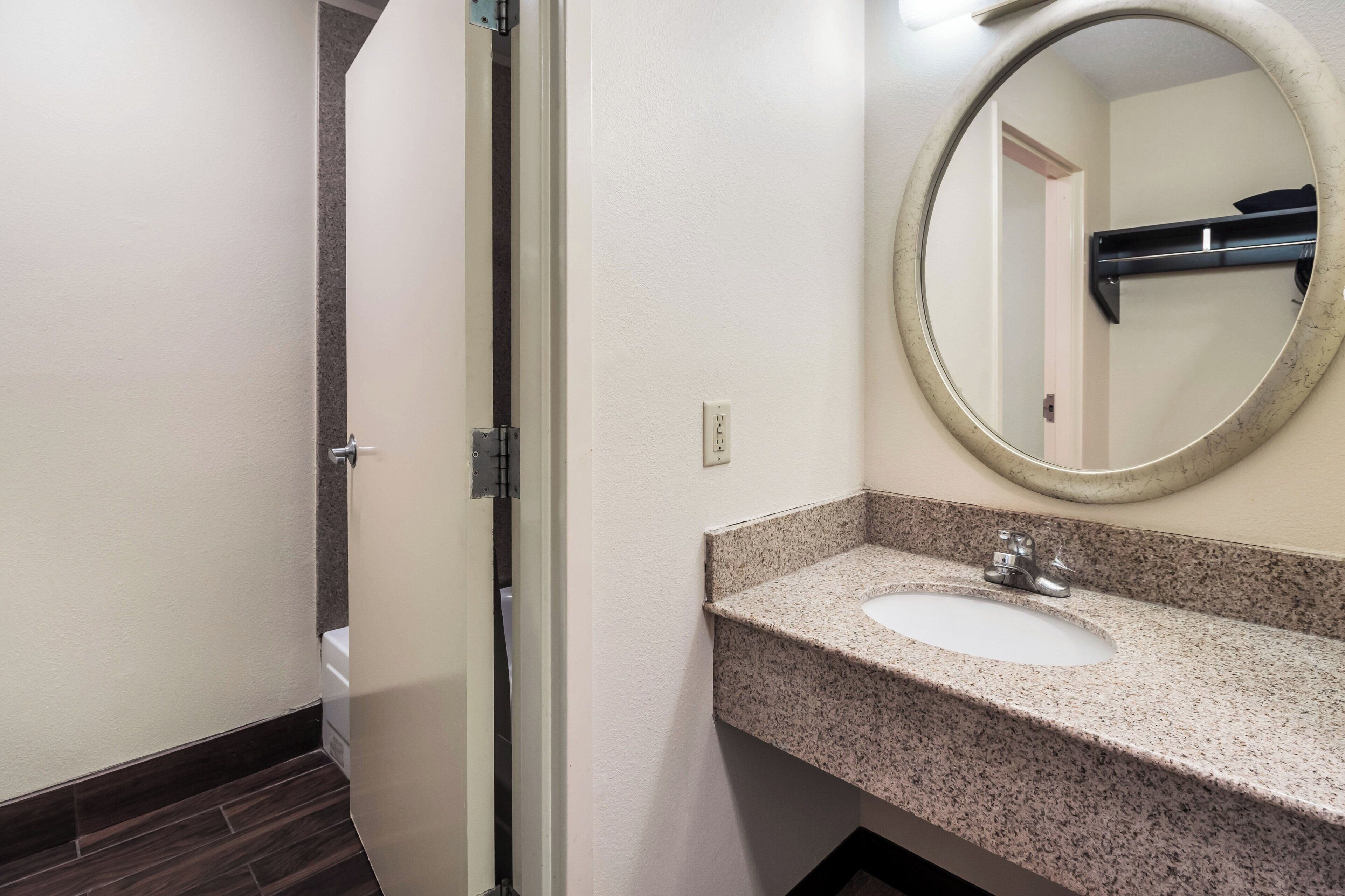 A bathroom with a sink, mirror, and a door leading to another room.
