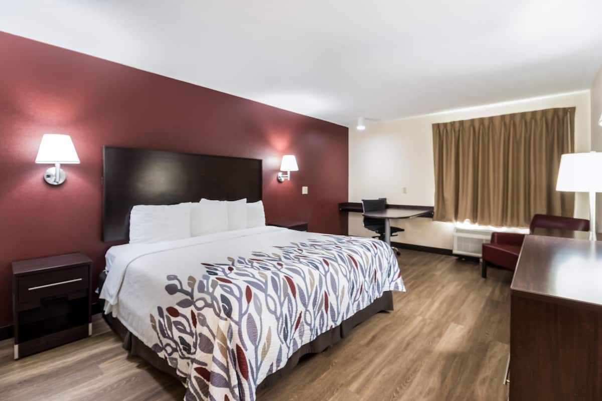 A hotel room with a bed, bedside tables, a desk, and a chair.