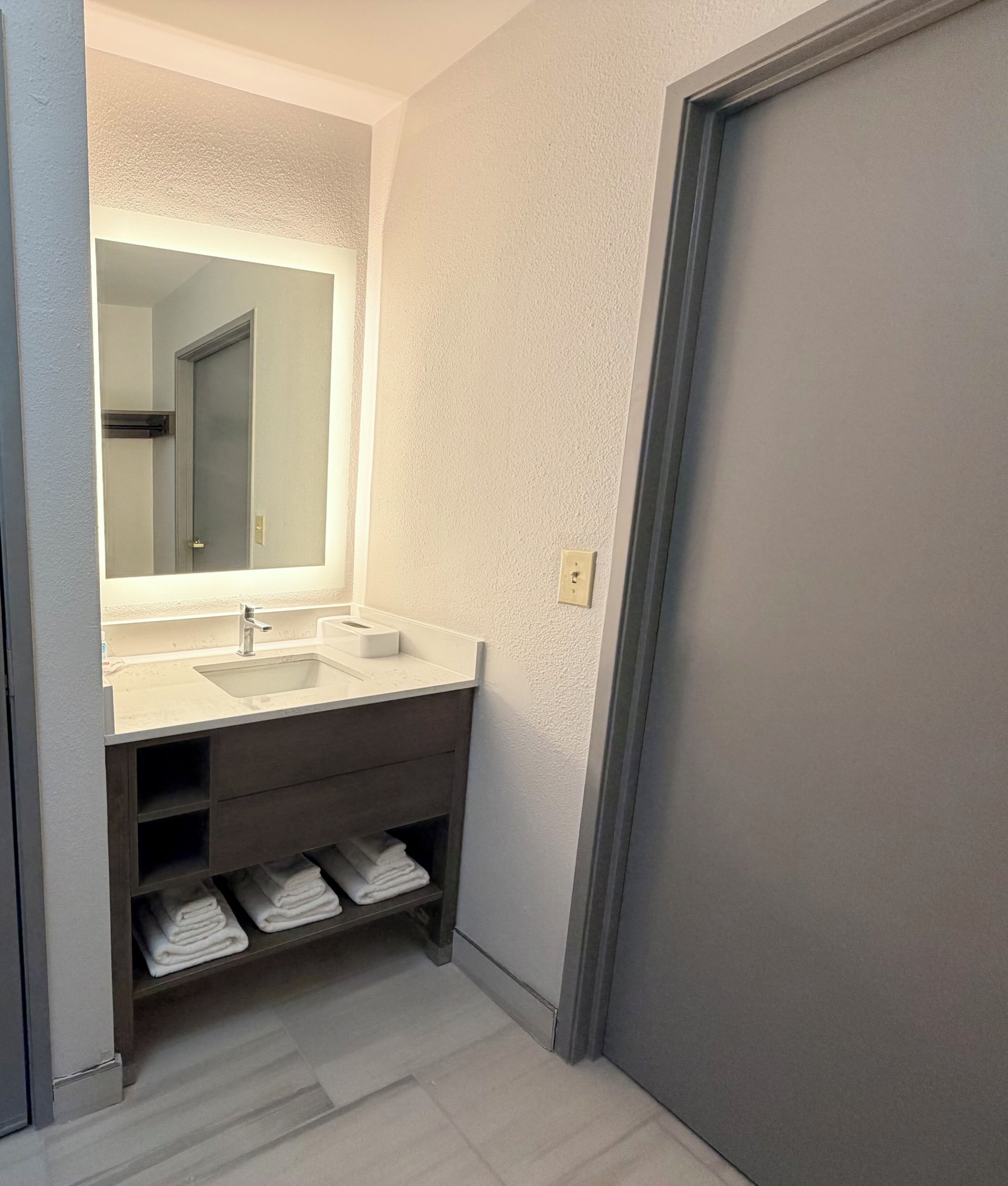 A bathroom with a large mirror, two sinks, and a towel rack.