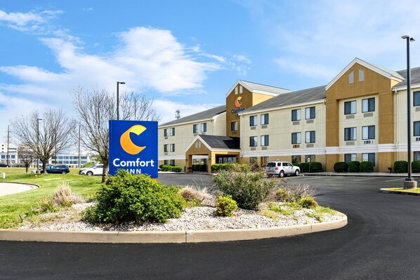 Ein Comfort Inn Hotel mit auffälliger Beschilderung, einem Parkplatz und einem Gebäude mit vielen Fenstern.