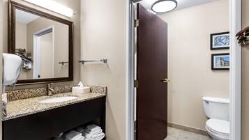 A bathroom with a sink, mirror, towel rack, toilet, and framed pictures on the wall.