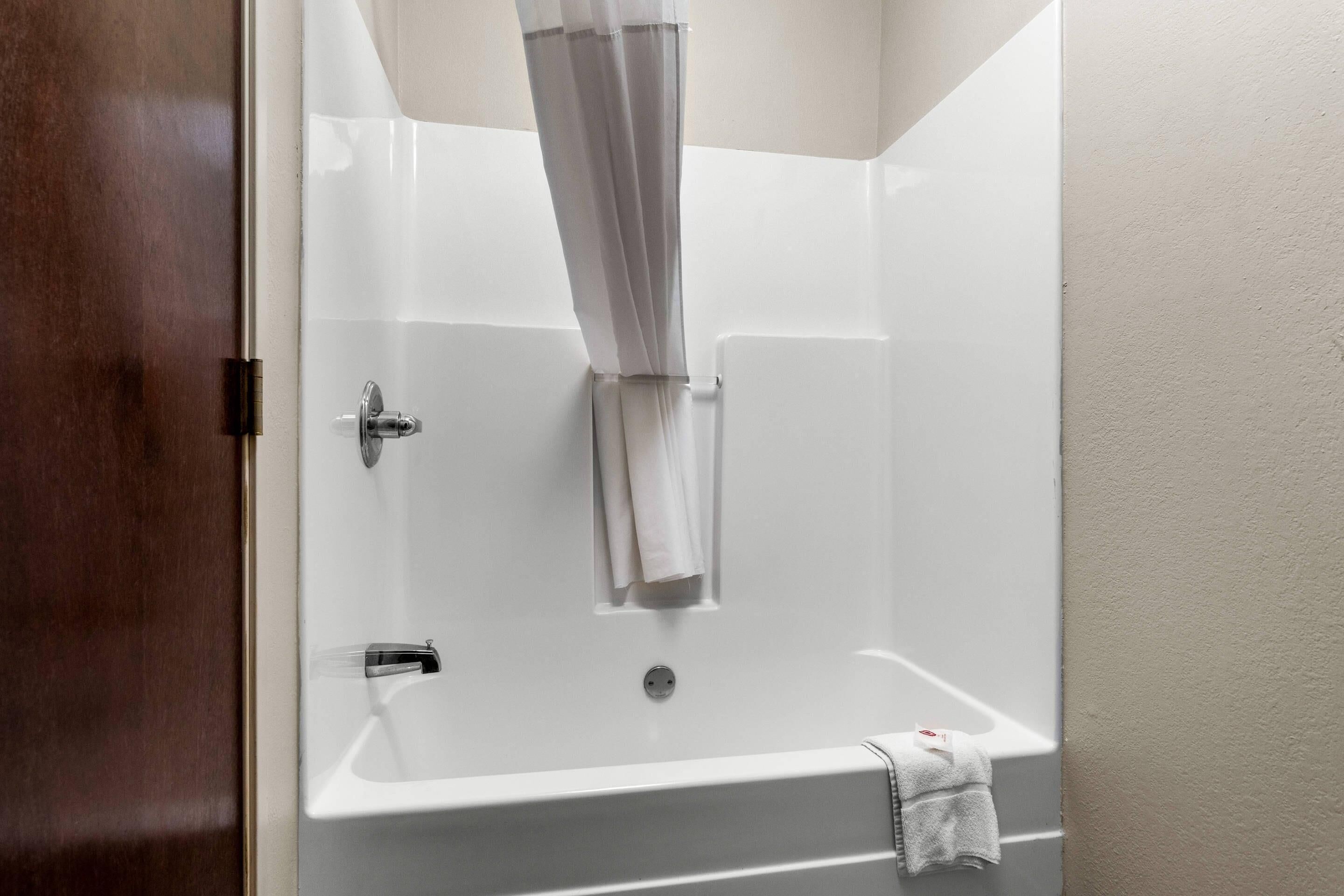 Une salle de bain avec une baignoire blanche, un rideau de douche et une serviette accrochée au mur.