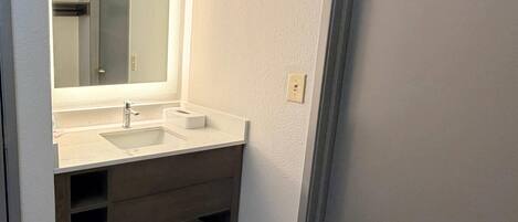 A bathroom with a double sink, a large mirror, and a towel rack.