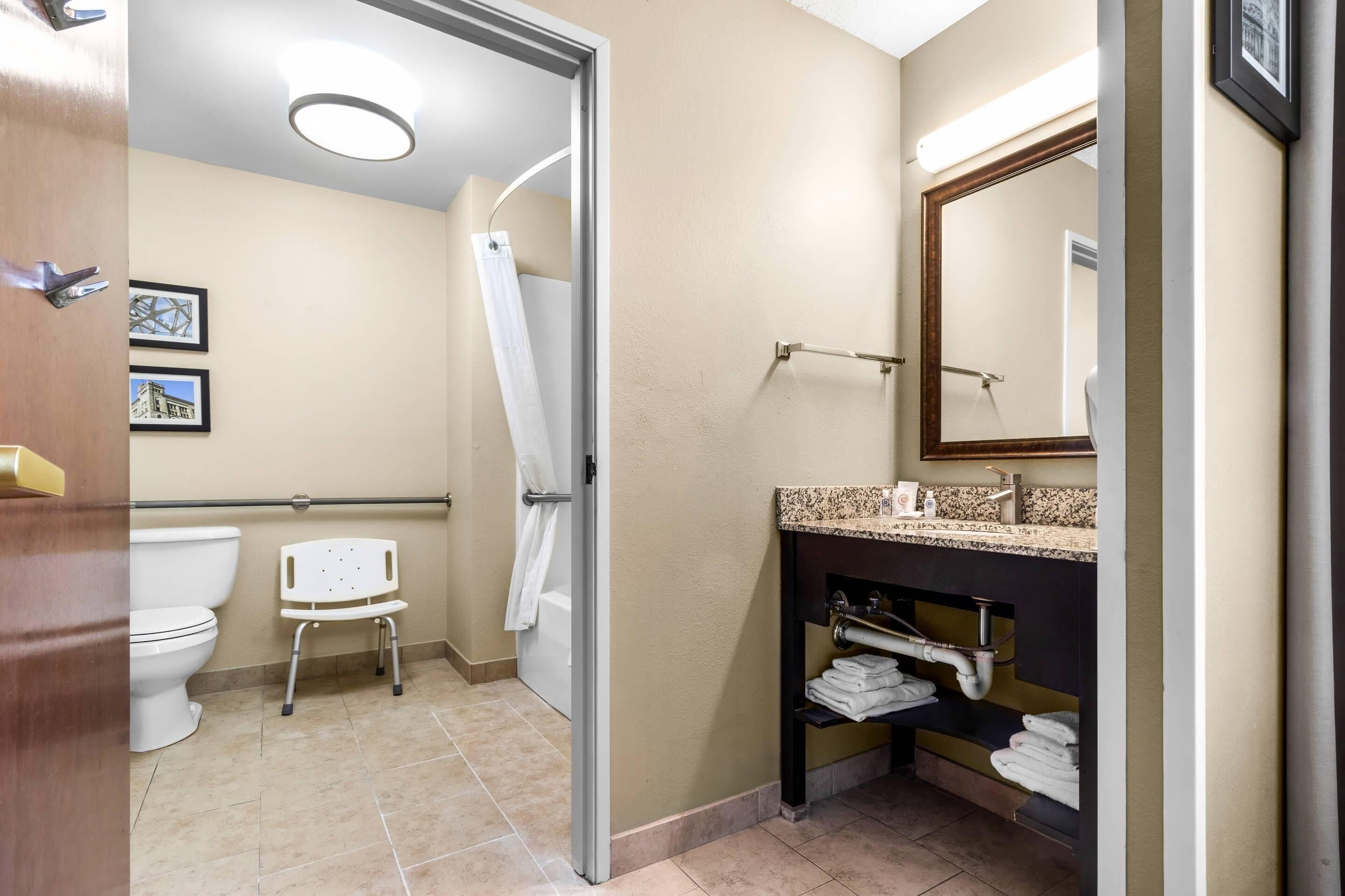 Een badkamer met een toilet, douche, wastafel en spiegel.