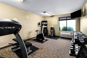 Ein Fitnessstudio mit Laufband, Crosstrainer und Kurzhanteln.