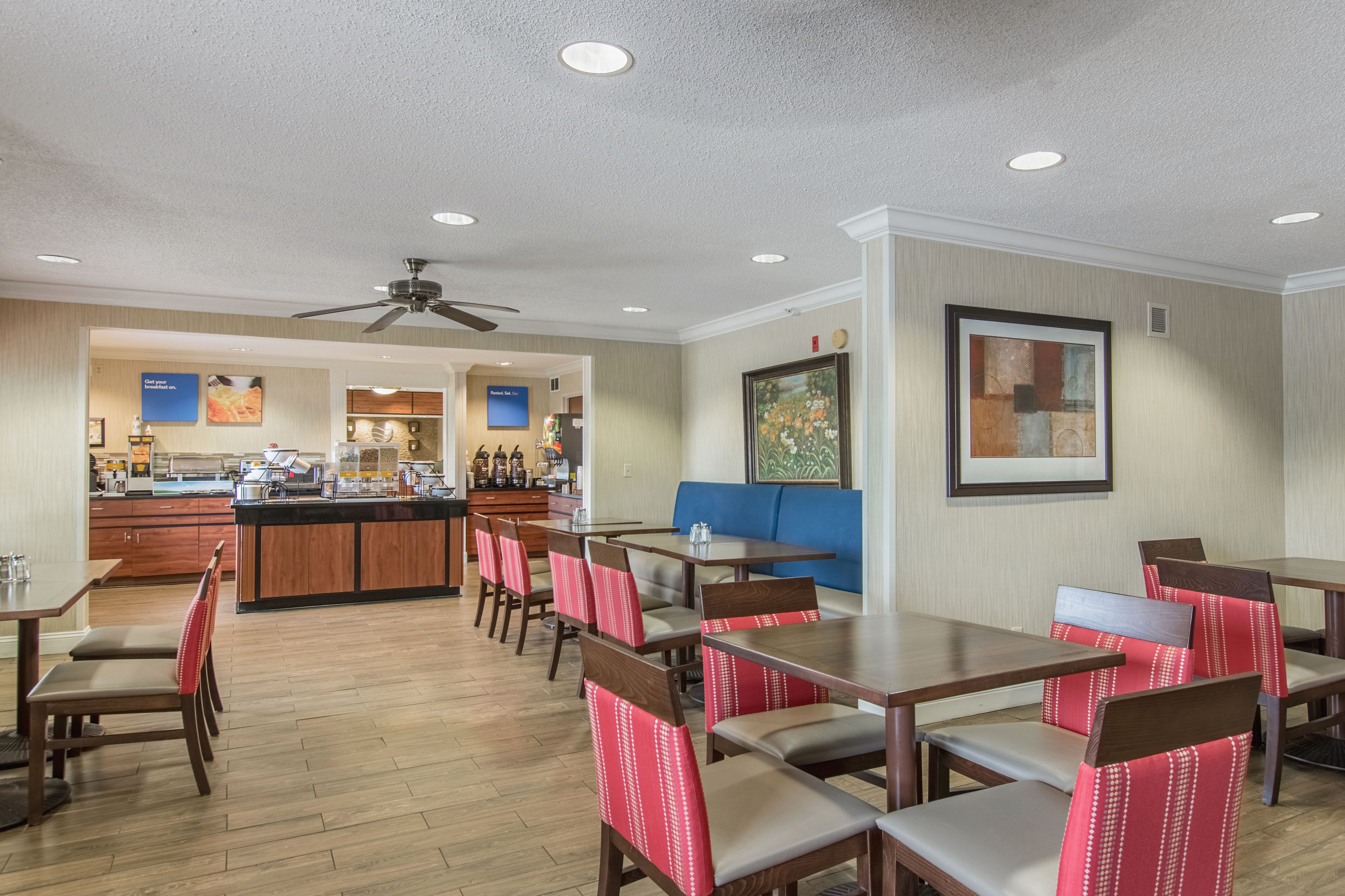 A restaurant with wooden tables and chairs, a counter, and a ceiling fan.