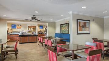 A restaurant with wooden tables and chairs, a counter, and a ceiling fan.