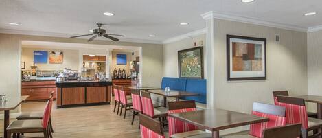 A restaurant with wooden tables and chairs, a counter, and a ceiling fan.