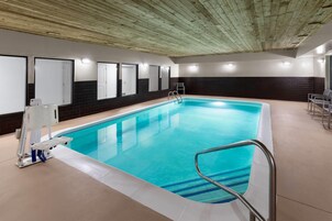 Una piscina interior con agua cristalina, una escalera y una silla para salvavidas.