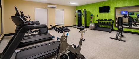 Un gimnasio con cinta de correr, bicicleta estática y máquinas de pesas.